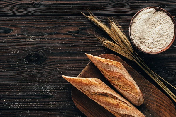 トップ ビューの配置部分のカッティング ボード 小麦のバゲットをフランスし 木製表面上のボウルに小麦粉 — ストック写真