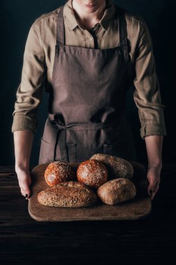ekmek üzerine siyah izole ahşap kesme tahtası üzerinde tutan kadın kısmi görünümünü loafs