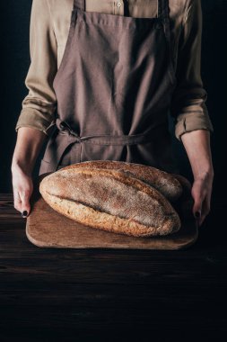 ekmek üzerine siyah izole ahşap kesme tahtası üzerinde tutan kadın kısmi görünümünü loafs