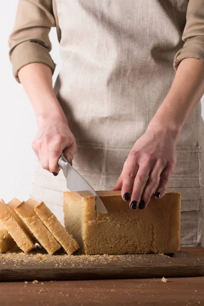 木製まな板の上の部分にパンを切る女性の部分的なビュー — ストック写真
