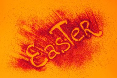 top view of easter sign made of red sand on orange surface clipart