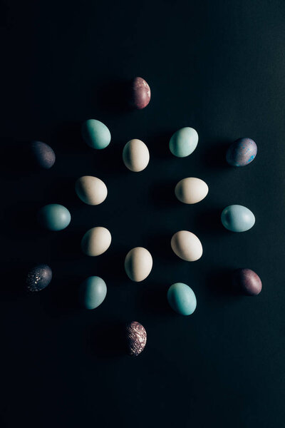 flat lay of colored painted easter eggs on dark surface