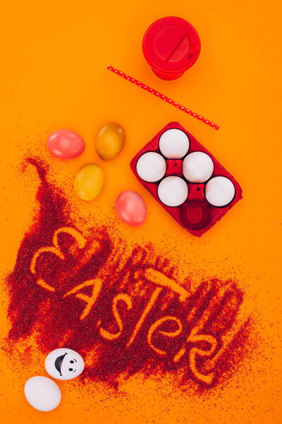 top view of easter sign made of red sand with chicken eggs and coffee on orange