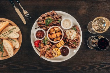ahşap masa üzerinde plaka sığır eti biftek, tavuk kanadı ve şarap ekmek ile Üstten Görünüm
