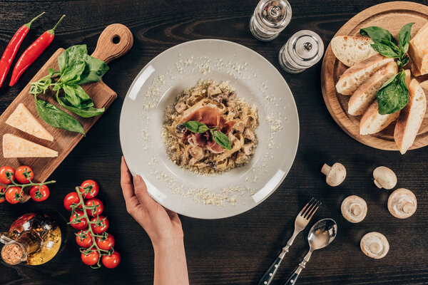 cropped image of woman holding plate with pasta and meat