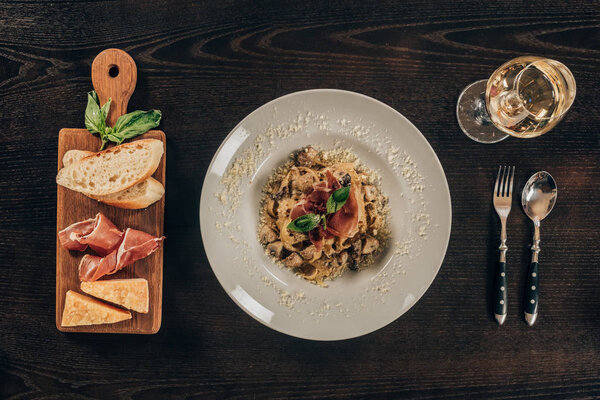 top view of pasta with meat and glass of wine on table