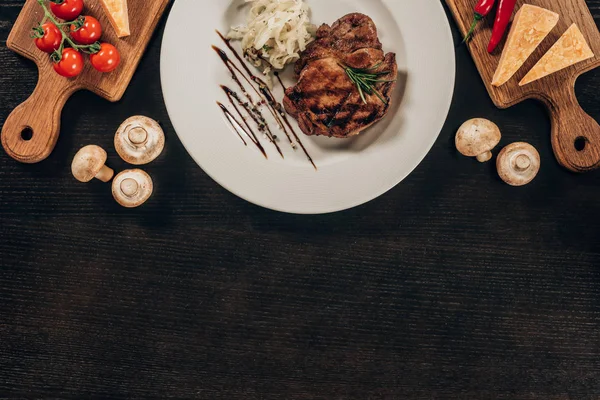 暗いテーブルの牛肉ステーキとオニオンのトップ ビュー — ストック写真