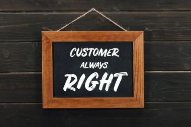 Board with lettering customer always right hanging on wooden wall clipart