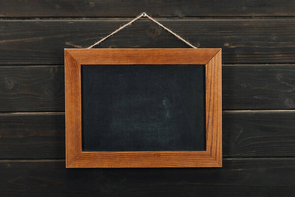 Empty blackboard hanging on wooden wall