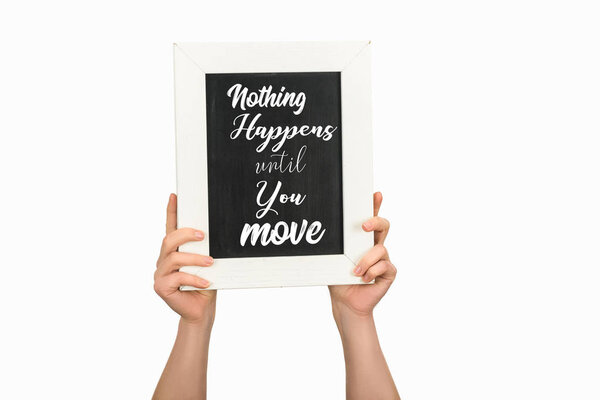 Cropped view of woman hands holding board with lettering nothing happens until you move isolated on white
