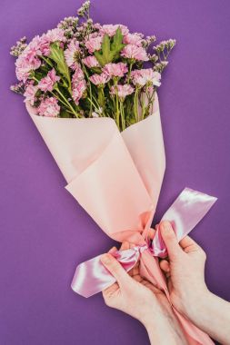 güzel çiçek buket pembe kurdele ile violet tutan kişi resmini kırpılmış  