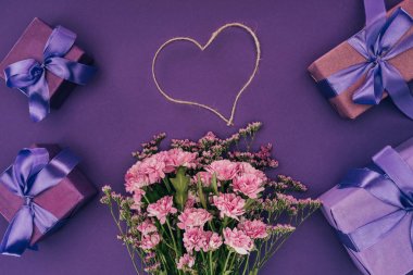 bouquet of beautiful pink flowers, heart-shaped rope and gift boxes on violet
