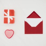 Vista superior del sobre rojo con papel en blanco y cajas de regalo aisladas en blanco