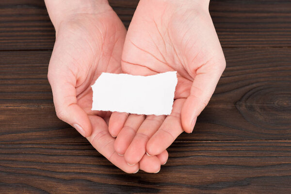cropped shot of woman holding blank paper over wooden table
