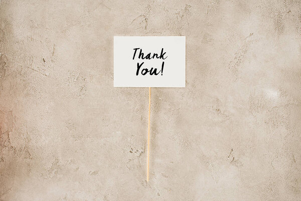 top view of thank you lettering on placard on concrete surface
