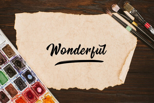 верхний вид старой бумаги с замечательными надписями и принадлежностями для покраски на деревянном столе
