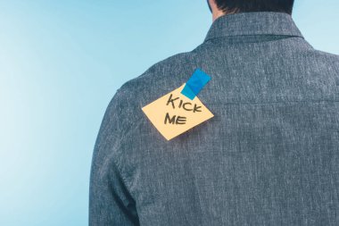 back view of man with note on sticky tape with kick me lettering on back, april fools day holiday concept clipart