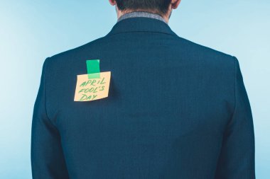 back view of businessman in suit with note with april fools day lettering on back, april fools day concept clipart