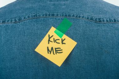 close up view of note with kick me lettering on jeans shirt, april fools day concept clipart