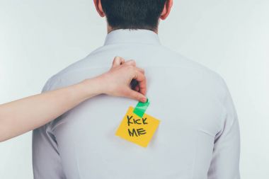 cropped shot of woman putting note with kick me lettering on males back, 1 april holiday concept clipart