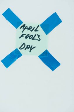 close up view of note with april fools day lettering and sticky tapes isolated on grey, april fools day concept clipart