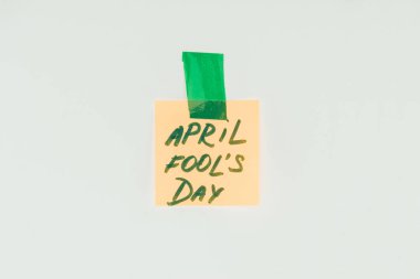 close up view of note with april fools day lettering and sticky tape isolated on grey, april fools day concept clipart