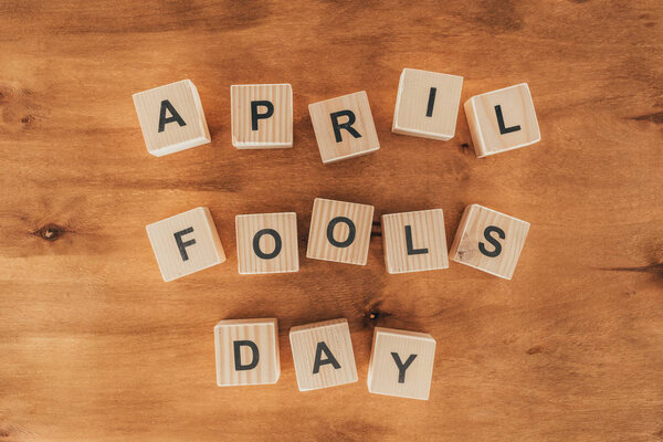 top view of arranged wooden cubes in april fools day lettering on wooden tabletop, 1 april holiday concept