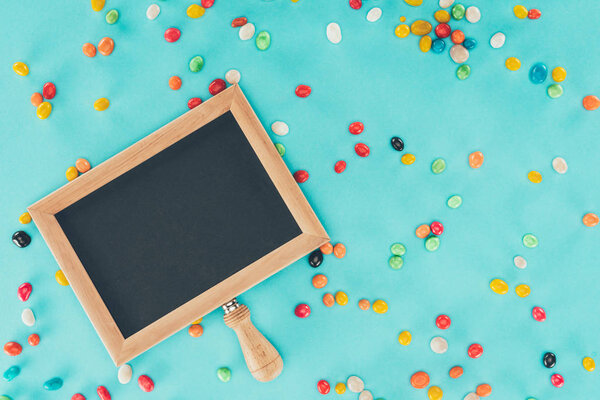 flat lay with empty blackboard and sweets isolated on blue surface, april fools day concept
