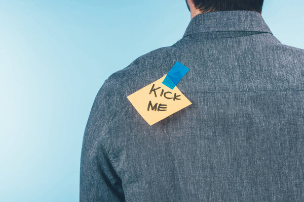 back view of man with note on sticky tape with kick me lettering on back, april fools day holiday concept