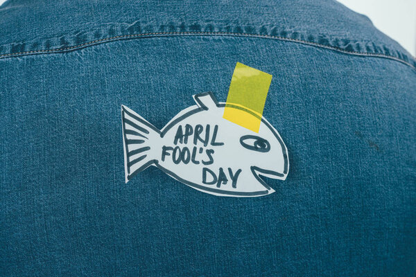close up view of paper made fish with sticky tape on jeans shirt, april fools day concept