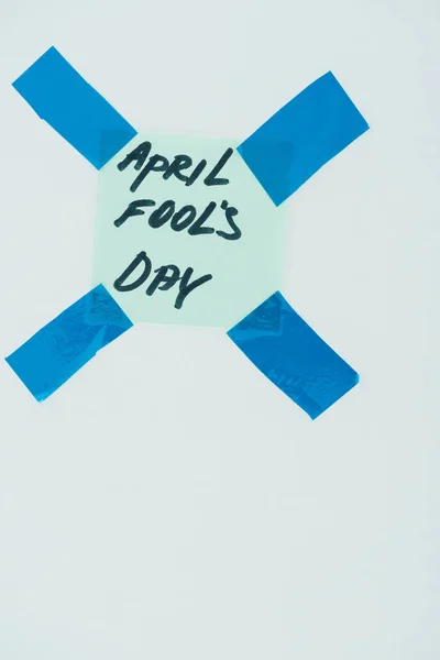 close up view of note with april fools day lettering and sticky tapes isolated on grey, april fools day concept