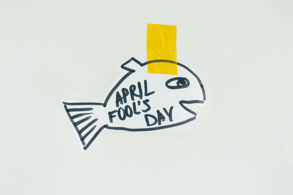 close up view of hand drawn fish with april fools day lettering and sticky tape isolated on grey, april fools day holiday concept