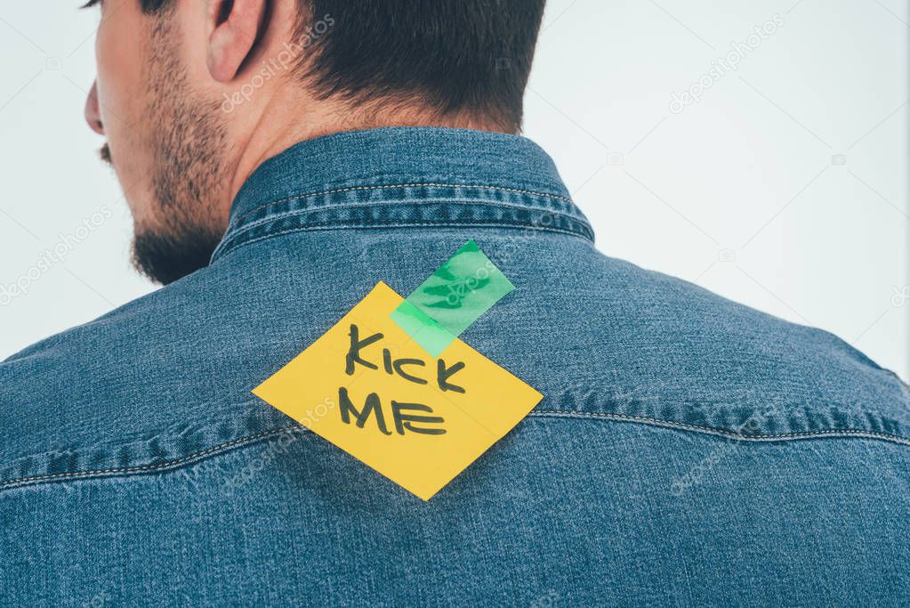 back view of man with note on sticky tape with kick me lettering on back, april fools day holiday concept