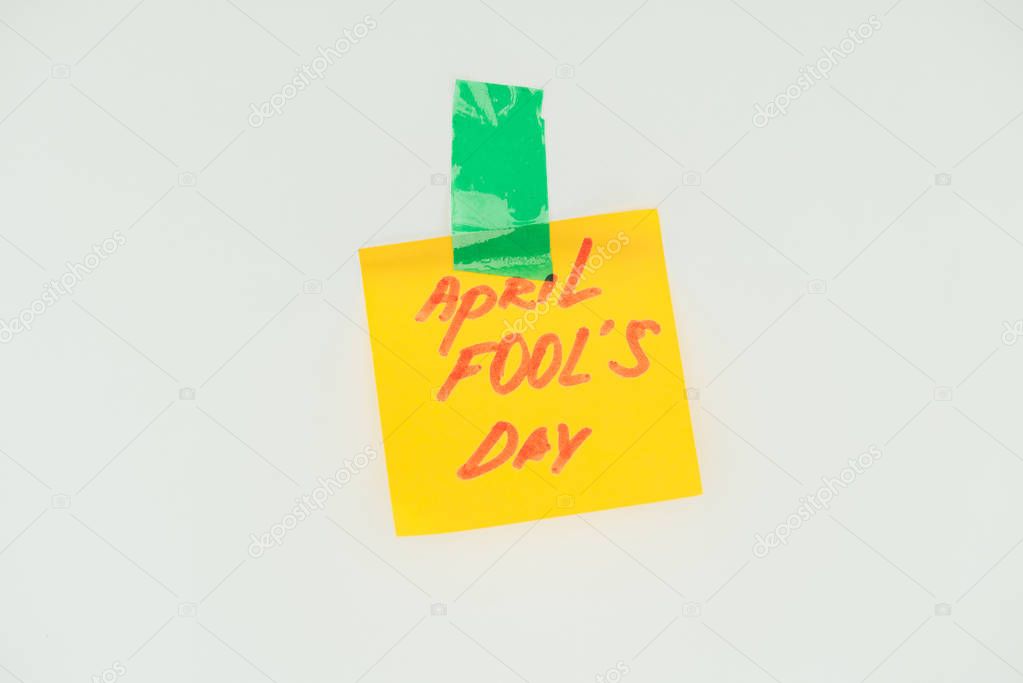 close up view of note with april fools day lettering and sticky tape isolated on grey, april fools day concept