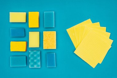 top view of yellow and blue washing sponges and rags isolated on blue clipart