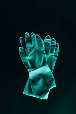 top view of protective rubber turquoise gloves isolated on black clipart