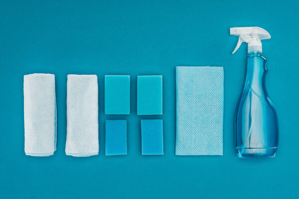 top view of rags, washing sponges and spray bottle isolated on blue