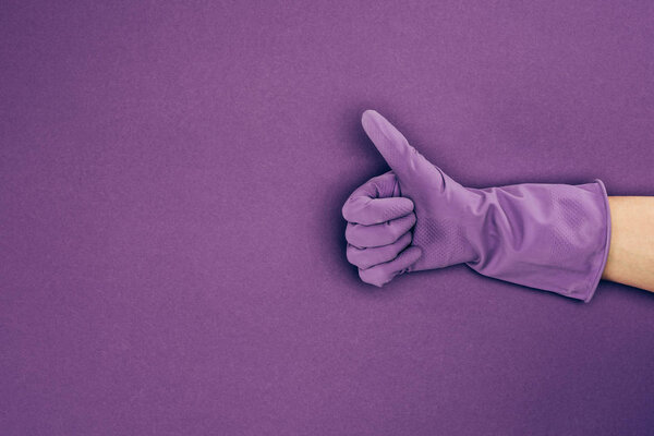 cropped image of woman showing thumb up in rubber protective glove isolated on violet