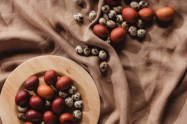 boyalı üstten görünüm Paskalya yumurta ve bıldırcın yumurtası ahşap plaka ve keten masa örtüsü