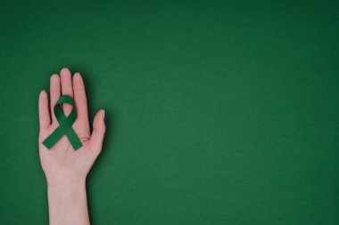 el ile yeşil farkındalık şerit yeşil farkındalık şerit için kırpılmış çekim skolyoz, ruh sağlığı sembol yeşil yüzey üzerinde izole için