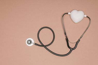 Düzenlenmiş kalp ve bej yüzeyinde, Dünya Sağlık günü kavramı izole stetoskop Üstten Görünüm