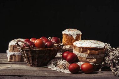 boyalı yumurta sepeti, willow twigs ve lezzetli Paskalya kek ahşap masa üzerinde görmek