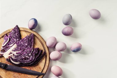 Grey ahşap kesme tahtası üzerinde mor boyalı yumurta ve mor lahana bıçakla Üstten Görünüm