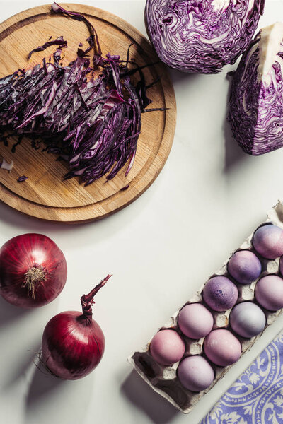top view of purple cabbage, onions and painted eggs in egg box on grey 