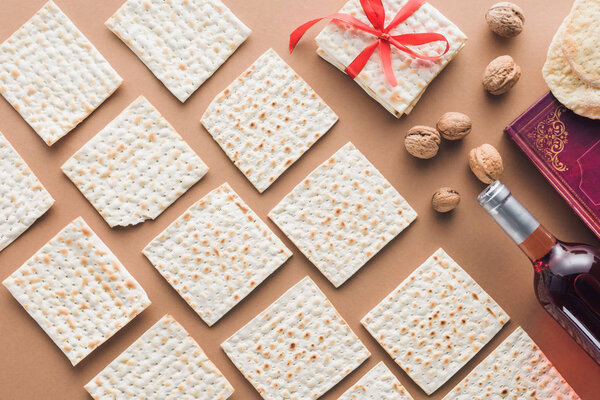 top view of traditional book with text in hebrew and collection of matza on brown table