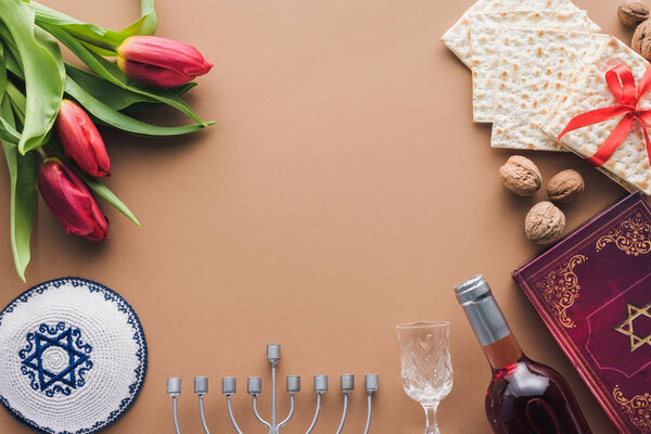 top view of traditional book with text in hebrew, menorah and kippah on brown surface
