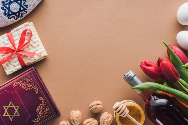 top view of traditional book with text in hebrew, wine and matza on brown table