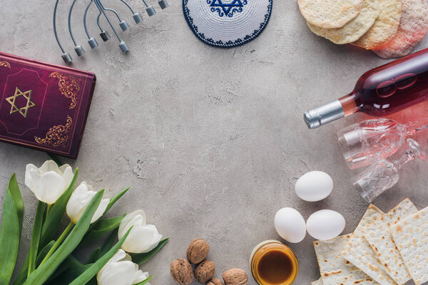 top view of traditional book with text in hebrew, menorah and kippah on concrete table