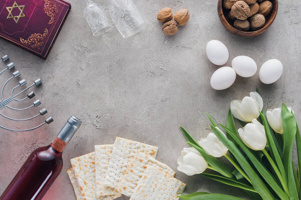 top view of traditional book with text in hebrew and matza on concrete table