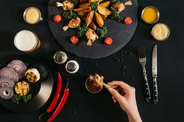 siyah soslu lezzetli tavuk kanadı tutan kişi kısmi Üstten Görünüm